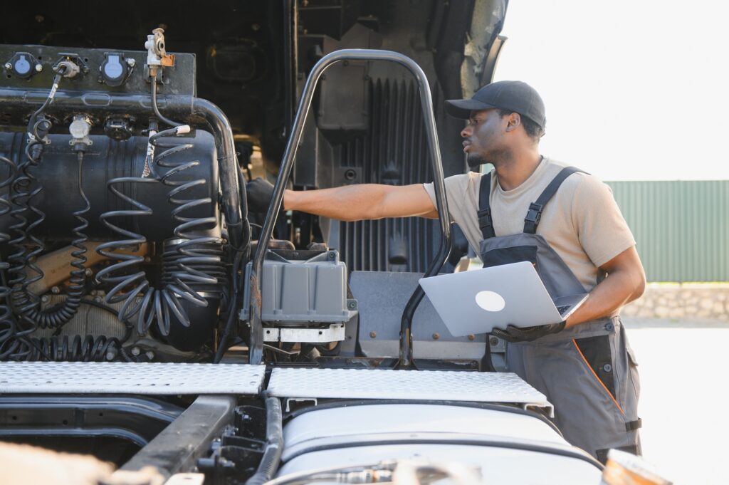 Truck repair service. African american Mechanic makes computer diagnostic of the semitruck Truck repair service. African american Mechanic makes computer diagnostic of the semitruck